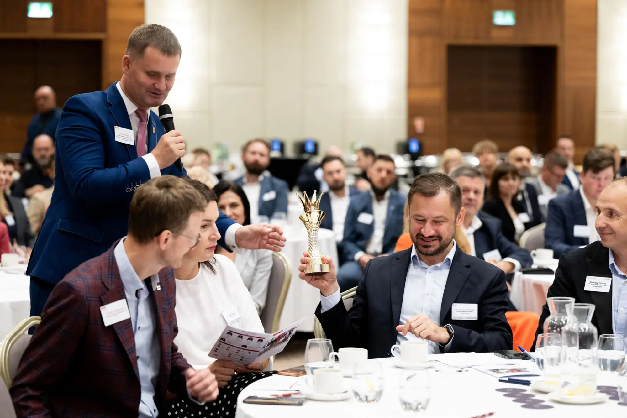 A BNI Member with a microphone at the table during a weekly Chapter Meeting