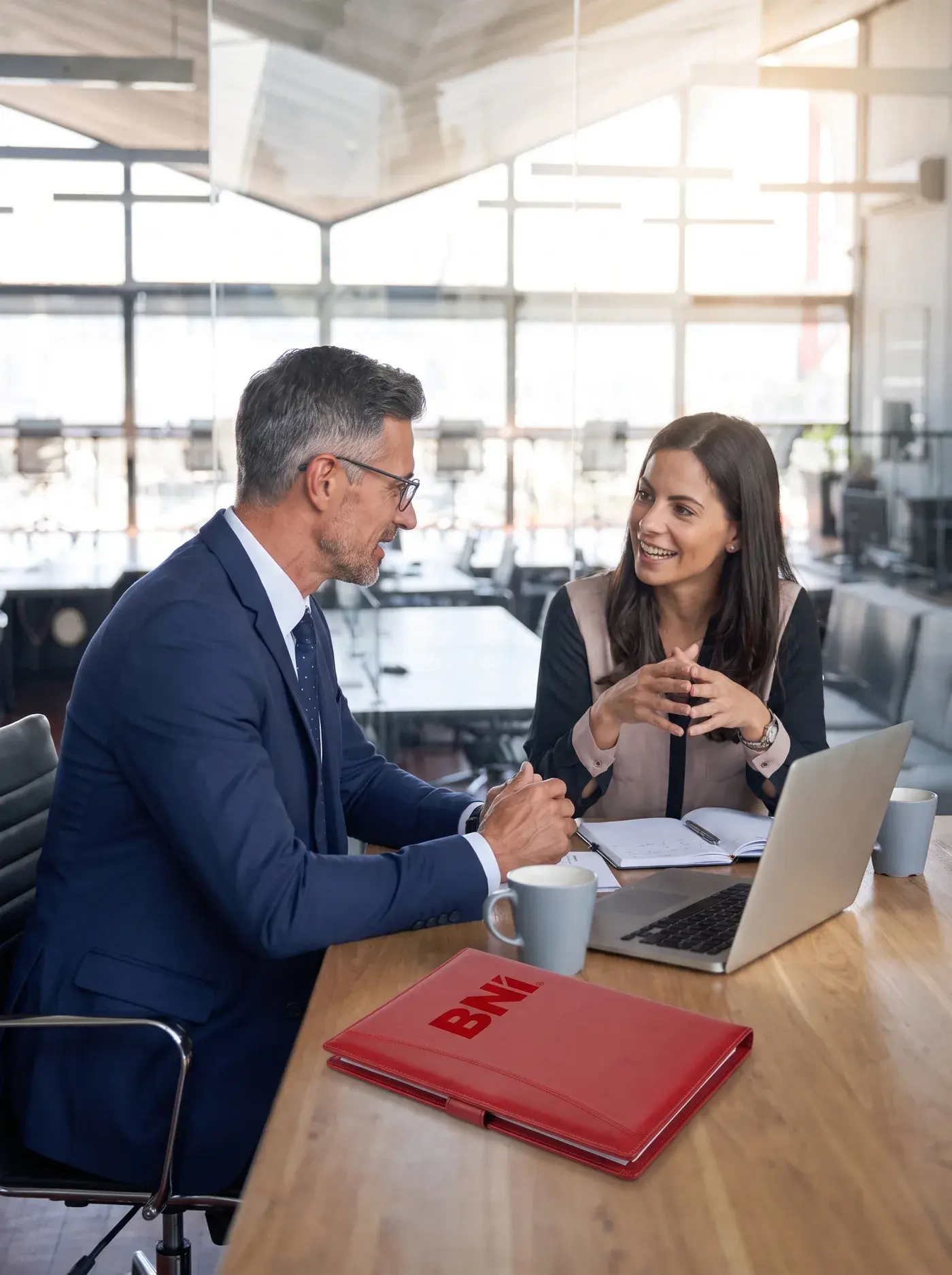 Two people at a table with a laptop in an office