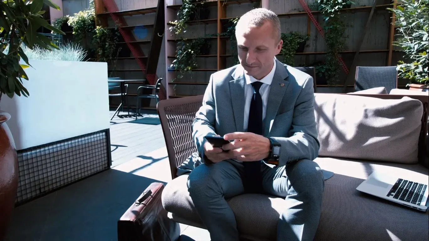 Grzegorz Wikar na tarasie z telefonem w dłoni