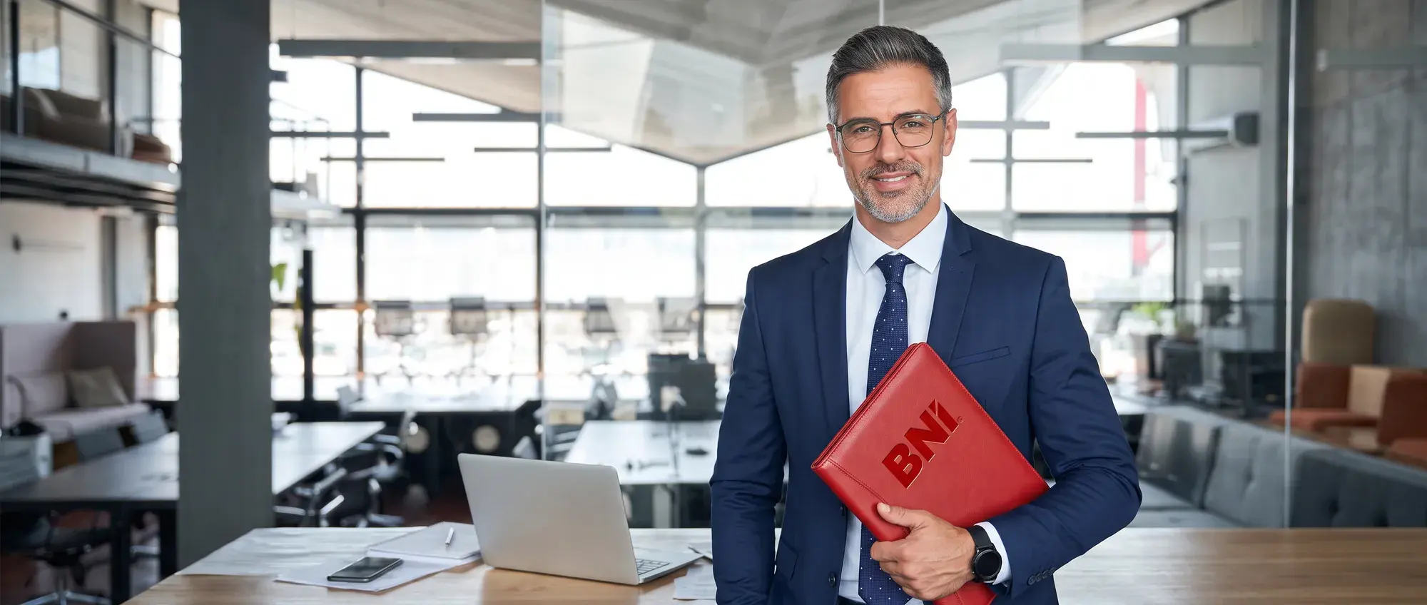 A smiling business owner with a red BNI folder in a modern office
