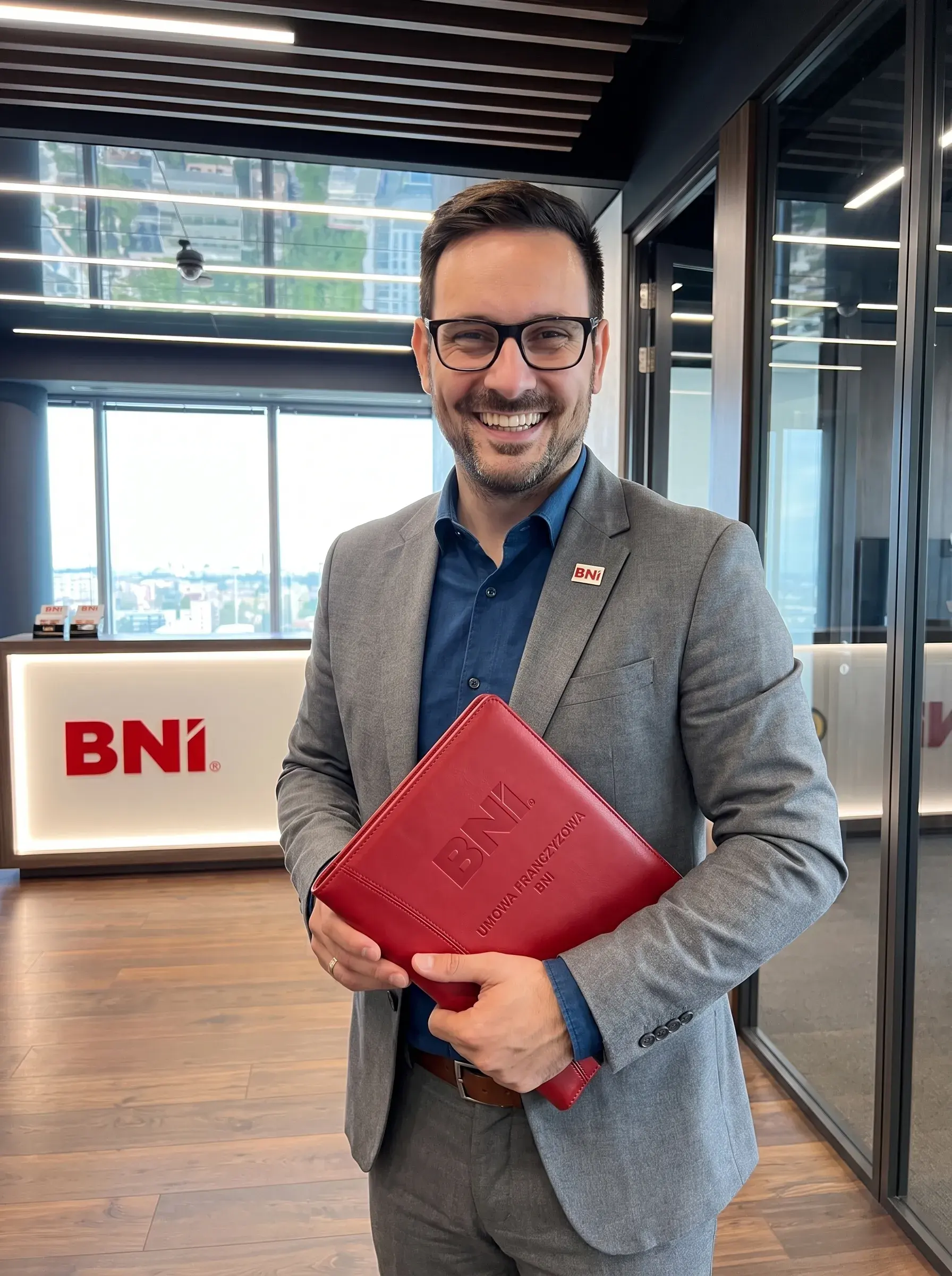 A Chapter leader with a red BNI folder smiles at the office reception