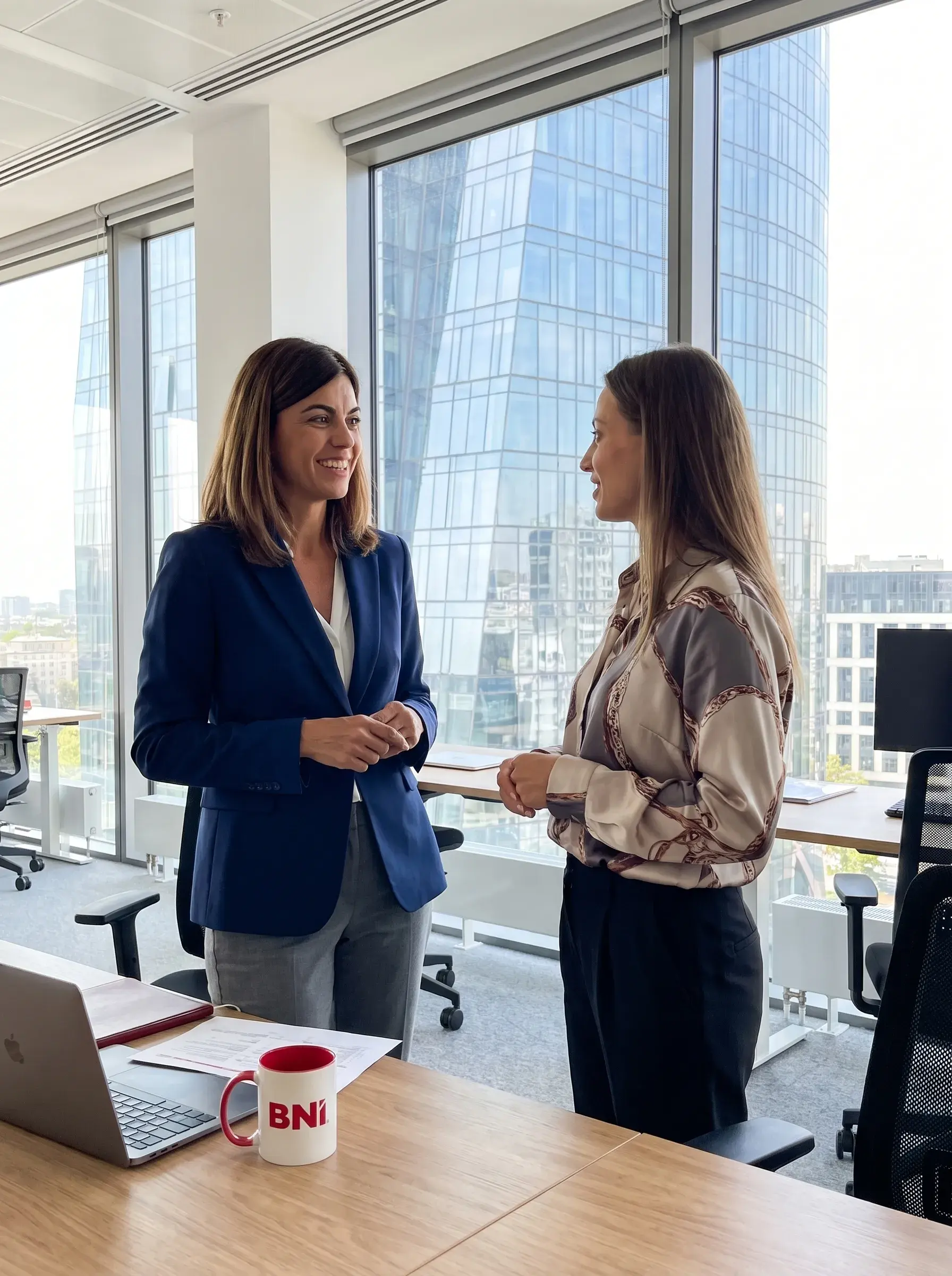 Two businesswomen talk by the window in an office