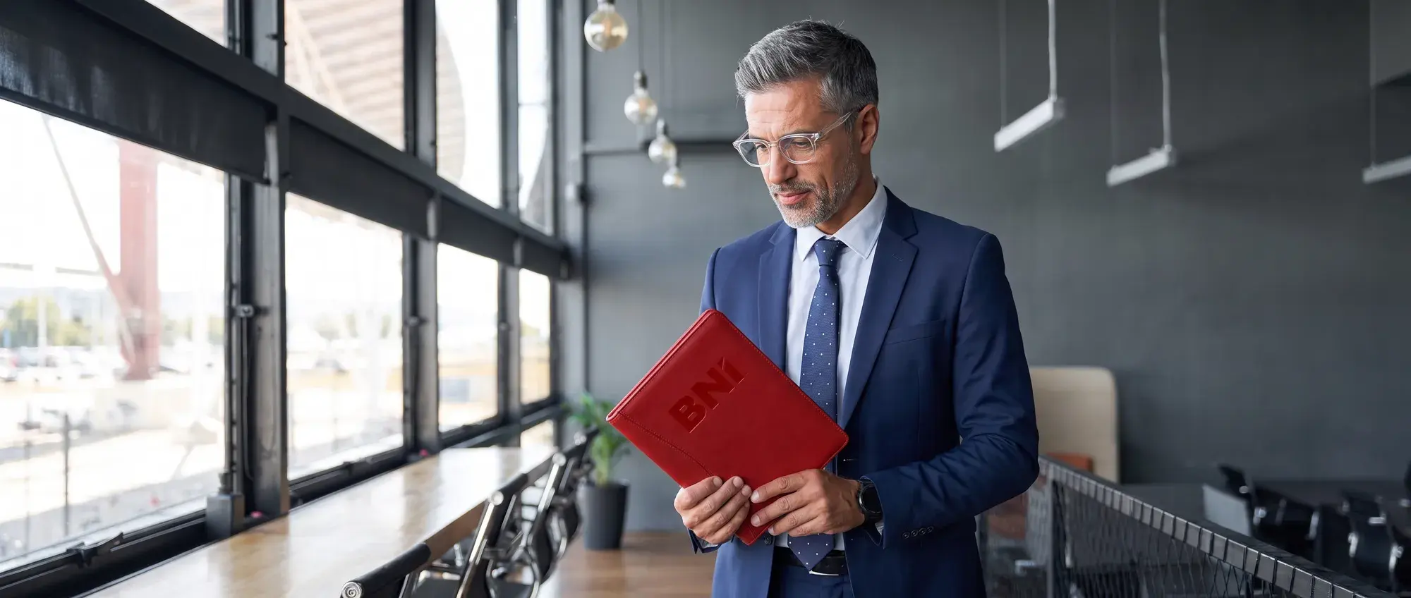 A business owner with a red BNI folder in a glass-walled office