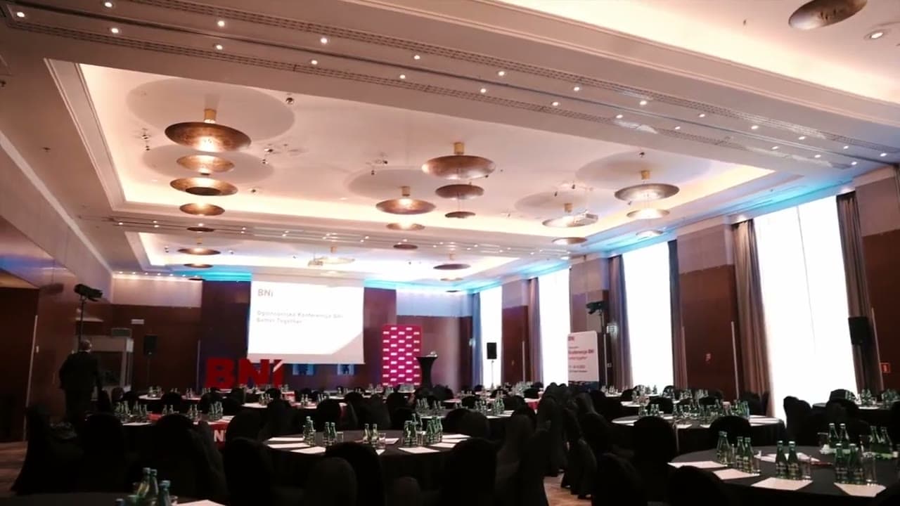 Footage from the BNI National Conference: a hall full of participants, a conversation at a table, a speaker in front of the audience