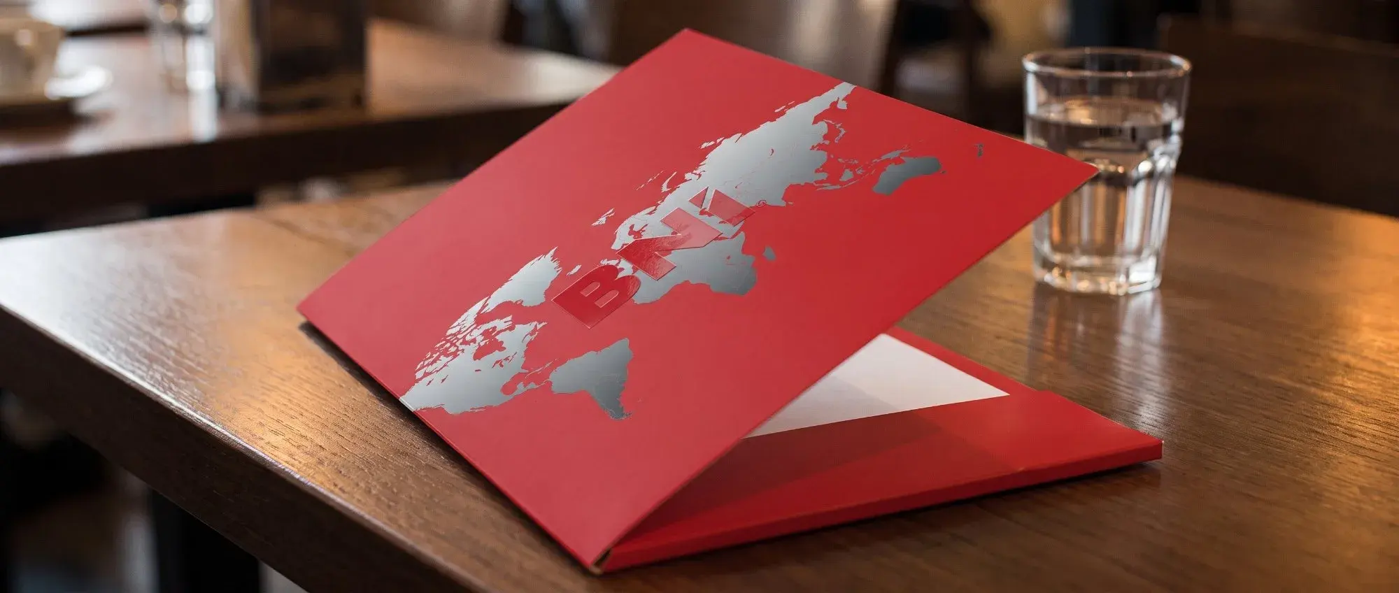 A red BNI folder with a world map on a table