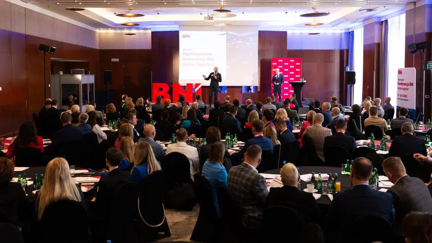 The BNI conference hall seen from above — full rows of chairs and a stage with a screen